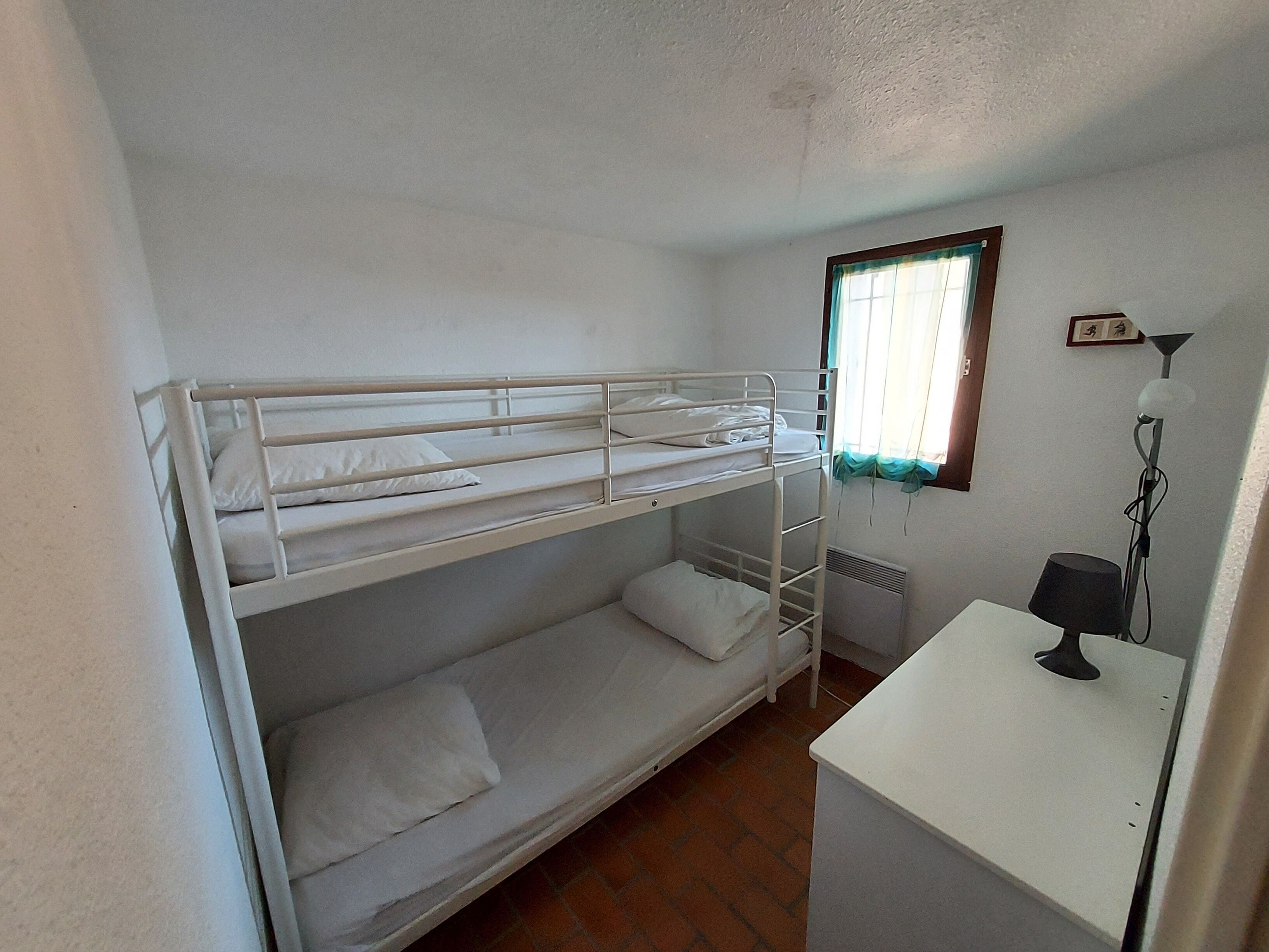 Une chambre avec un lit superposé, un bureau et une lampe.