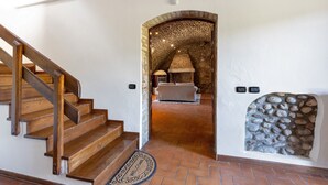 A staircase leading to a room with a stone wall and a fireplace.