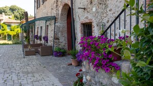 A stone building with a covered outdoor seating area, potted plants, and a staircase.