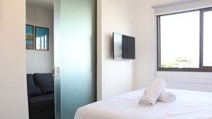 Habitación de hotel con cama, televisión montada en la pared y ventana con vistas al exterior.