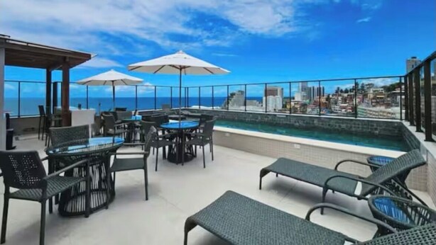 Terraza en la azotea con piscina, mobiliario exterior y vistas a la ciudad.