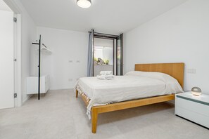A bedroom with a wooden bed, a bedside table, a wardrobe, and a mirror.