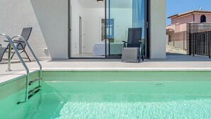 En swimmingpool med en ingångsdörr av glas, en stol och en metallstege.