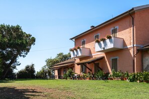 Um edifício de dois andares com varanda, área de estar ao ar livre e gramado bem cuidado.