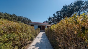 A pathway leading to a building with a tiled roof, surrounded by dense shrubbery. - Holiday Home 'Mirella- Portobello' with Private Terrace, Private Garden and Wi-Fi (Portobello)