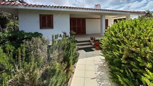 A white building with a tiled roof, a covered porch, and a garden with various plants. - Holiday Home 'Mirella- Portobello' with Private Terrace, Private Garden and Wi-Fi (Portobello)