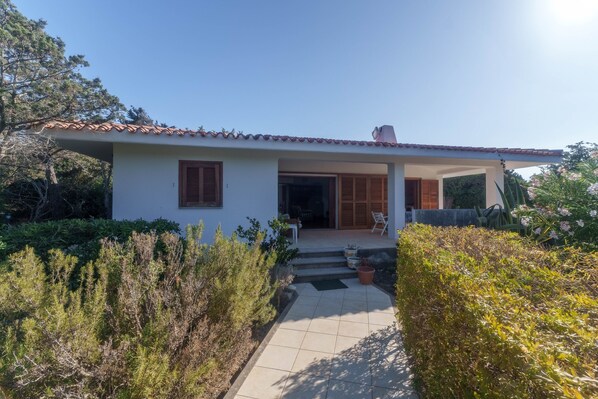 A single-story house with a tiled roof, a front door, and a small porch area.