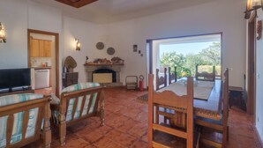 A living room with a fireplace, a television, and a dining area with a table and chairs. - Holiday Home 'Mirella- Portobello' with Private Terrace, Private Garden and Wi-Fi (Portobello)