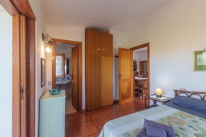 A bedroom with a bed, a dresser, a mirror, and a door leading to another room.