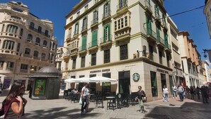 A building with a Starbucks coffee shop on the ground floor, featuring outdoor seating and a manhole cover in the center. - Felix Sáenz Boutique Suites: Design Stay in Malaga Center (Málaga)