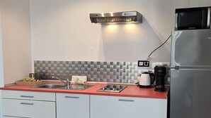 A modern kitchen with a stainless steel refrigerator, a microwave, a kettle, and a coffee maker. There is a sink with a faucet, a countertop, and a tiled backsplash. - Felix Sáenz Boutique Suites: Design Stay in Malaga Center (Málaga)