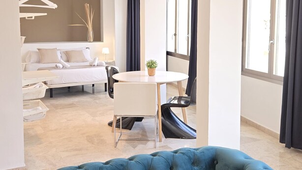 A modern hotel room with a bed, bedside table, lamp, and a round table with chairs. - Felix Sáenz Boutique Suites: Design Stay in Malaga Center (Málaga)