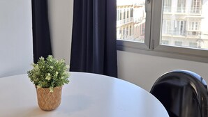 A room with a round table, a potted plant, a chair, and a window with curtains. - Felix Sáenz Boutique Suites: Design Stay in Malaga Center (Málaga)
