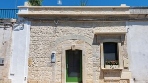 A stone building with a green door, a small window with flowers, and a sign above the door.