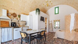 A compact kitchen with a dining area, a small refrigerator, and a hanging plant.