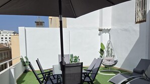 A rooftop terrace with a table and chairs, a hanging chair, and a small garden area. - Modern Suites in Malaga Center (Málaga)