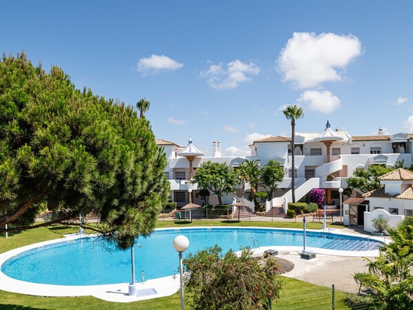 A resort with a swimming pool, multiple-story buildings, and a well-maintained lawn.