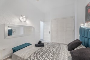 A bedroom with a bed, a bench, a mirror, a wardrobe, and a door. - Vacation 'Garden View' with Mountain View, Shared Pool and Private Garden (Costa Adeje)