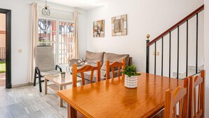 A dining area with a wooden table and chairs, a potted plant, and a staircase with a railing.