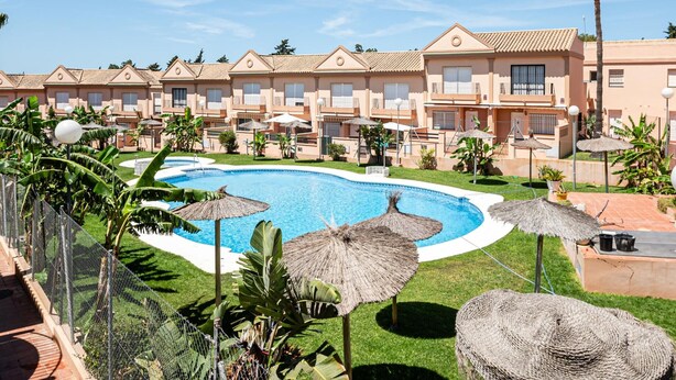 A resort with a central swimming pool, multiple guest rooms, and tropical landscaping.