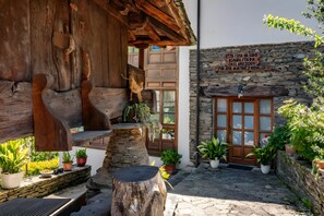 Un bâtiment rustique en bois, avec un mur en pierre, une porte en bois et des plantes en pot.