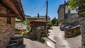 A narrow street with stone buildings, a wooden house, and parked cars. - Apartment 'Puente Del Narcea 3' with Mountain Views, Private Terrace and Wi-Fi (Cibuyo)