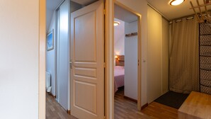 Corredor que leva a um quarto com uma cama, um radiador e uma porta.