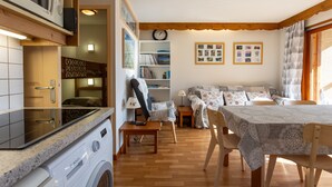 Um espaço de estar compacto com máquina de lavar, mesa de jantar, sofá e estante.