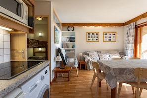 Un ambiente compatto con lavatrice, tavolo da pranzo, divano e libreria.