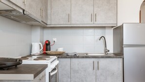Une cuisine moderne avec des meubles gris, une cuisinière blanche, un évier et un réfrigérateur blanc.