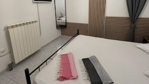 Une chambre d’hôtel équipée d’un lit, d’une télévision, d’un climatiseur, d’un radiateur et d’une fenêtre avec des rideaux.