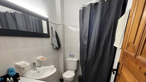 Une salle de bain moderne équipée d’un lave-linge, d’un lavabo, de toilettes et d’un rideau de douche.