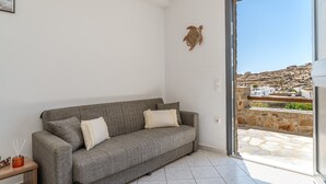 Un canapé gris avec des coussins blancs, une petite table avec une bougie et un élément décoratif fixé au mur.