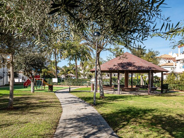A park with a paved walkway, a gazebo, and playground equipment.