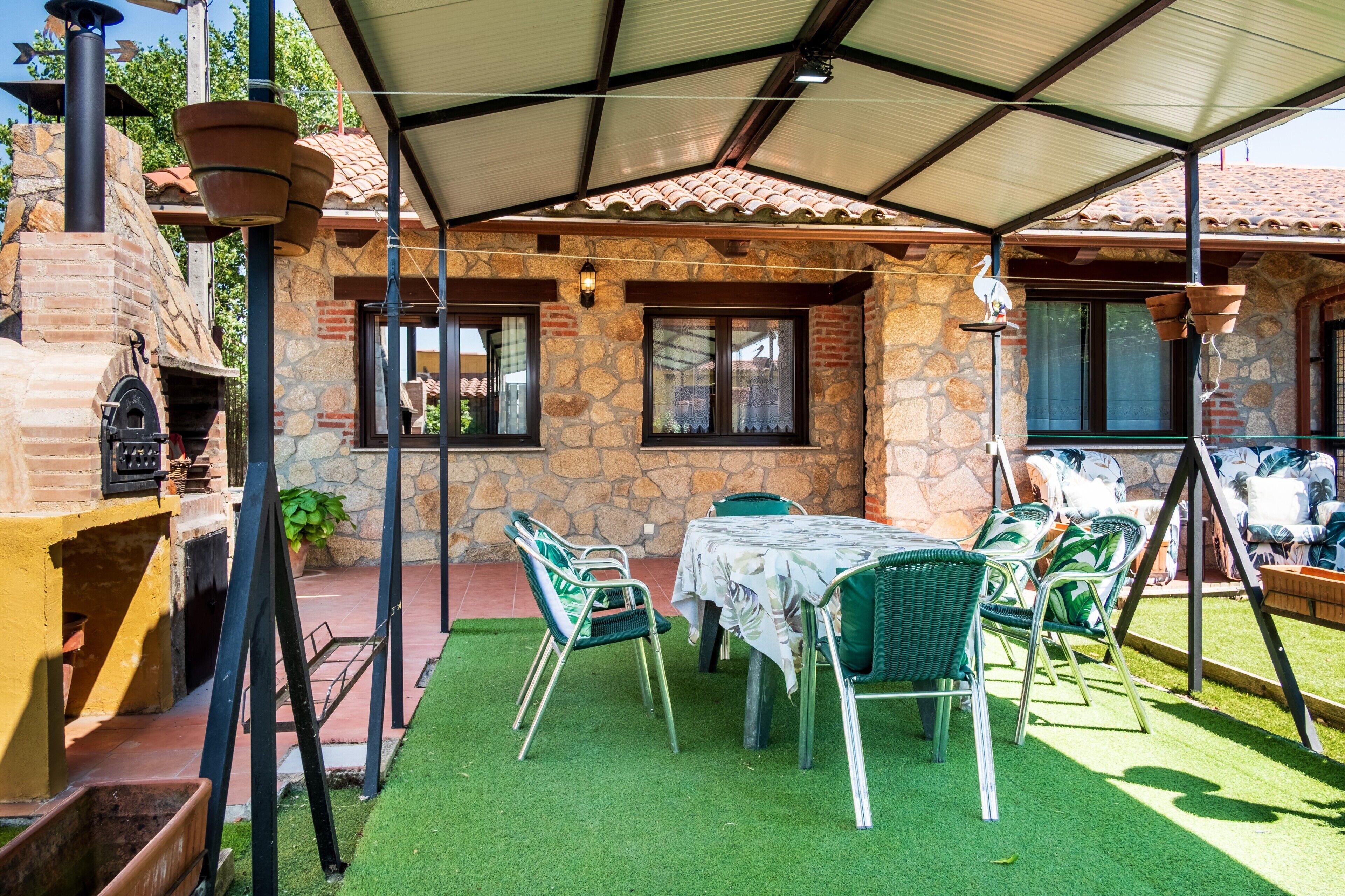 A patio area with a stone wall, a brick oven, and outdoor seating.