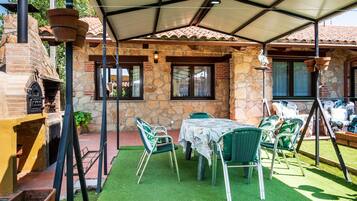 A patio area with a stone wall, a brick oven, and outdoor seating.