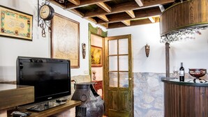 A kitchen with a TV, a large pot, a wooden counter, and a stone wall.