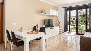 Una sala de estar moderna con comedor, televisor y balcón con vistas.