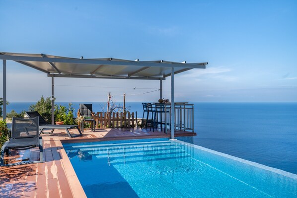 A pool with a view of the sea, a covered seating area, and lounge chairs. - Country House 'Sea View 2' with Sea View, Wi-Fi and Air Conditioning (Lefkada)