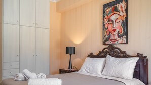 A neatly made bed with white linens, a painting on the wall, and a nightstand with a lamp. - Country House 'Sea View 2' with Sea View, Wi-Fi and Air Conditioning (Lefkada)