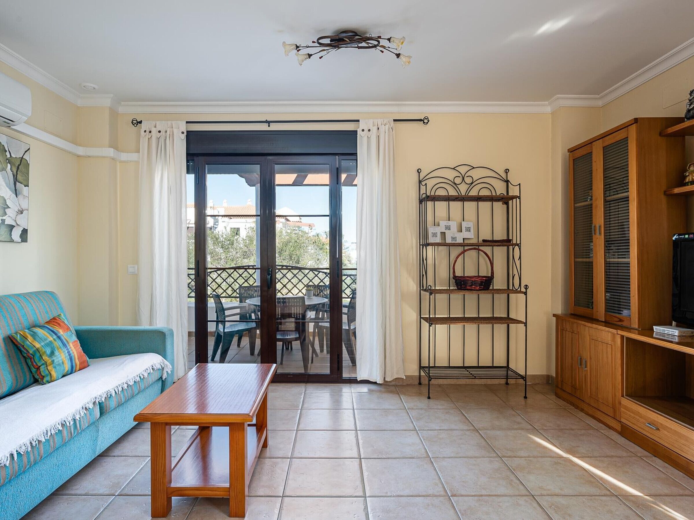 A living room with a sofa, a wooden table, a metal shelf unit, and a wooden cabinet.