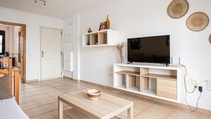 A modern living room with a flat-screen TV, wooden coffee table, and built-in shelves.