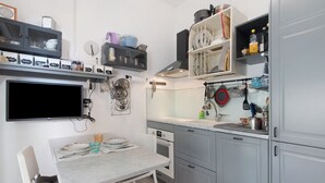 A compact kitchen with a dining table, built-in oven, and various kitchen utensils. - ‘Terrazzo Del Gelsomino’ Apartment with Private Terrace (Rapallo)