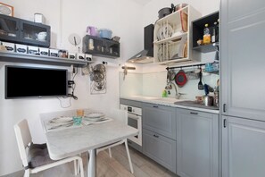 A compact kitchen with a dining table, built-in oven, and various kitchen utensils.