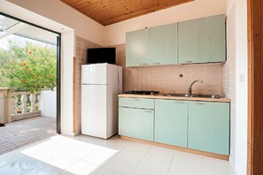 Een koelkast, een kookplaat, kookgerei, borden en bestek