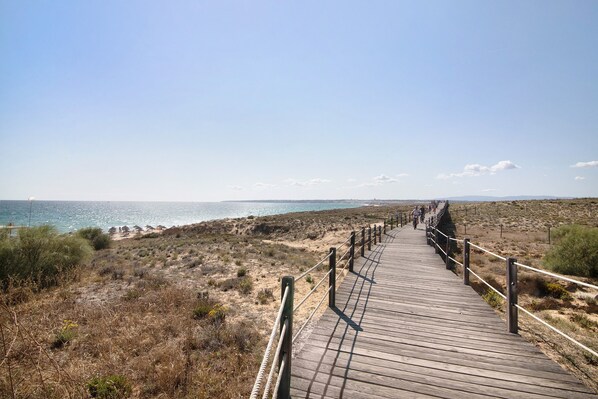 A wooden boardwalk leading to a beach with a clear sky.