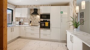A modern kitchen with white cabinets, a microwave, oven, and a plant on the counter. - Apartment 'Salgados Beach House' with Shared Pool, Wi-Fi and Air Conditioning (Albufeira)