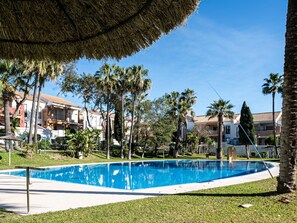 Una piscina rodeada de palmeras y un edificio con techo de tejas.