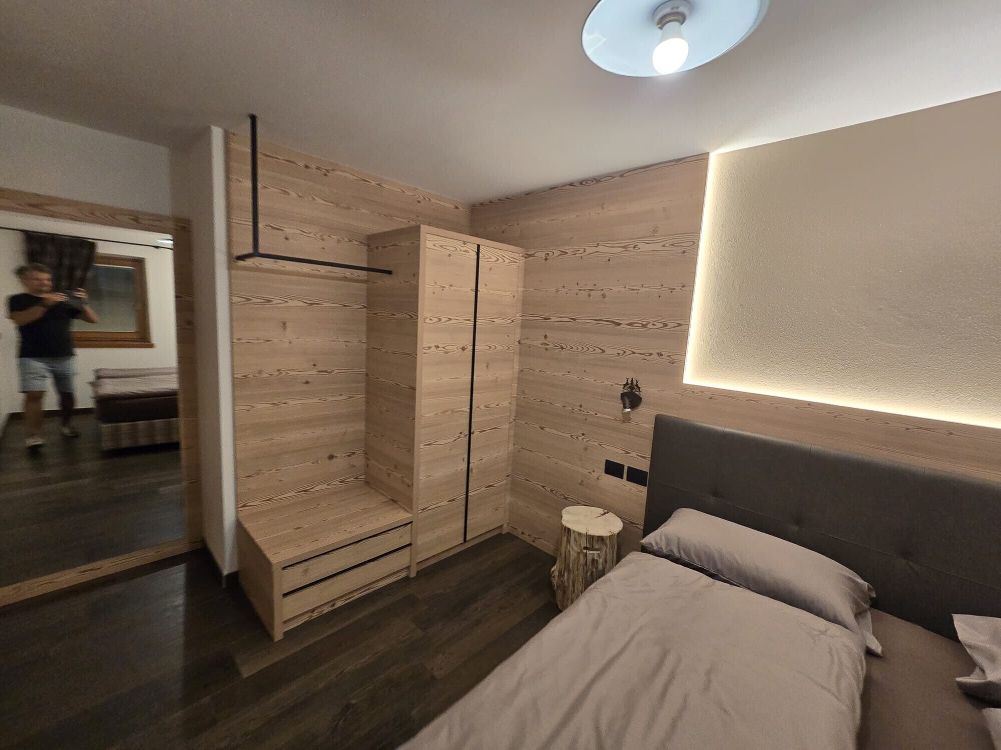 A modern bedroom with a bed, bedside tables, a wardrobe, and a mirror.