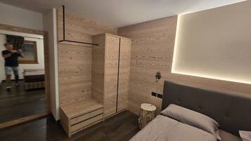 A modern bedroom with a bed, bedside tables, a wardrobe, and a mirror.